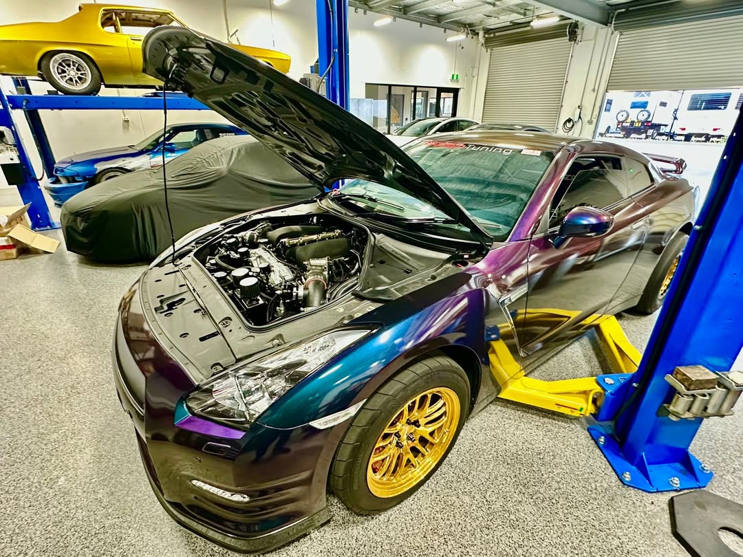 The workshop's chameleon purple R35 GT-R roll racing car on the hoist with its built VR38 engine exposed