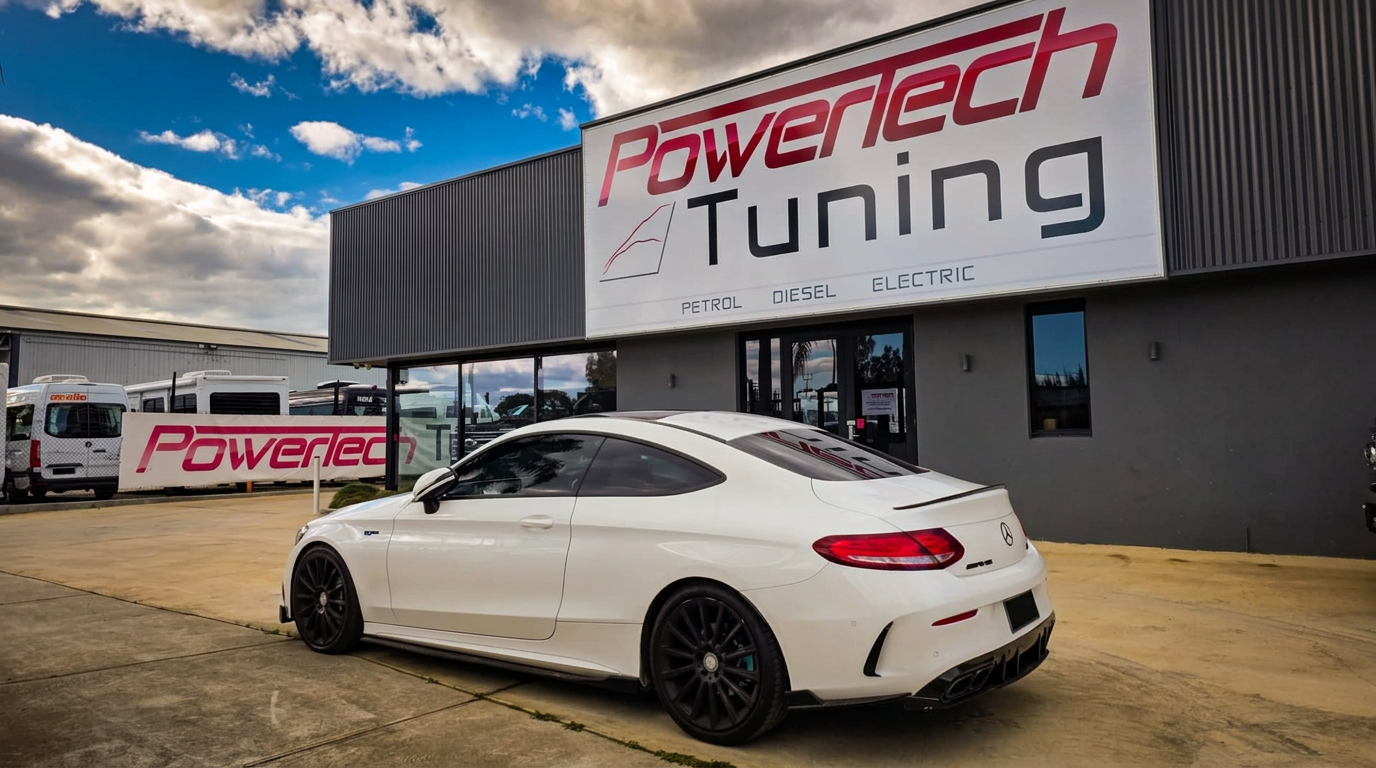 White Mercedes-AMG C63 coupe parked under the Power Tech Tuning building sign