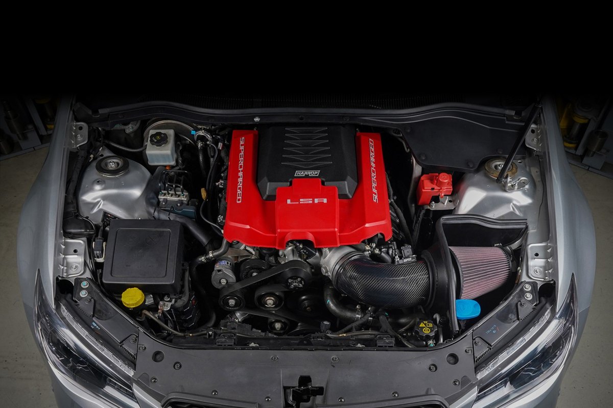 Harrop supercharged LSA engine bay with red coil covers and a carbon intake